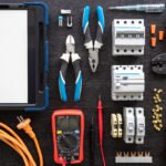 Flat lay composition with electrical tools and digital tablet on wooden background.